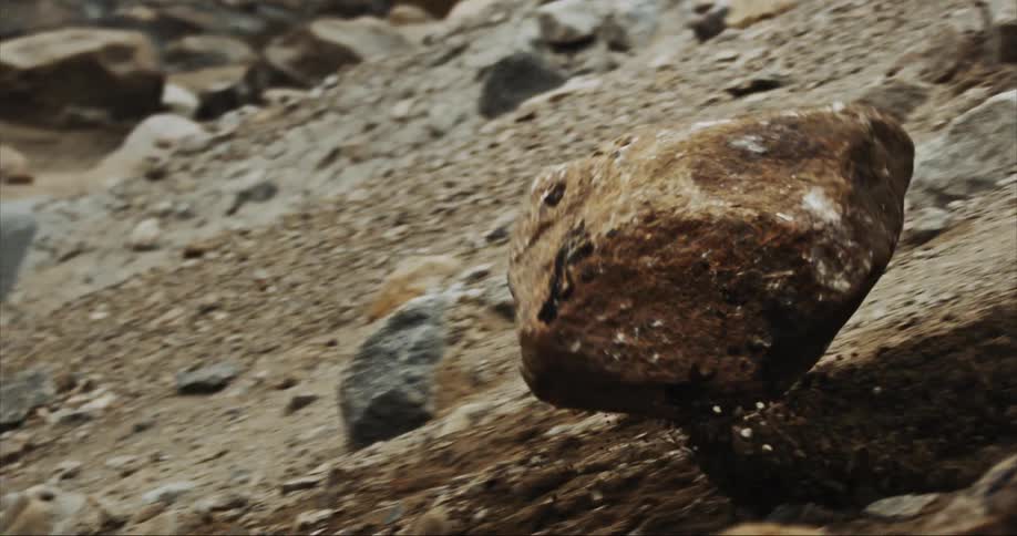 A massive boulder tumbles down into a river valley, erosion in progress