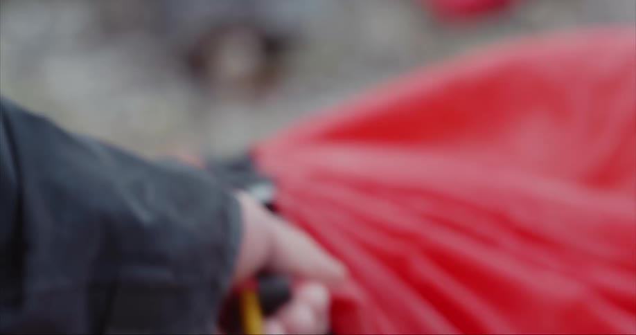 Man with black jacket puts up a rent tent in a glacial valley near the arctic circle