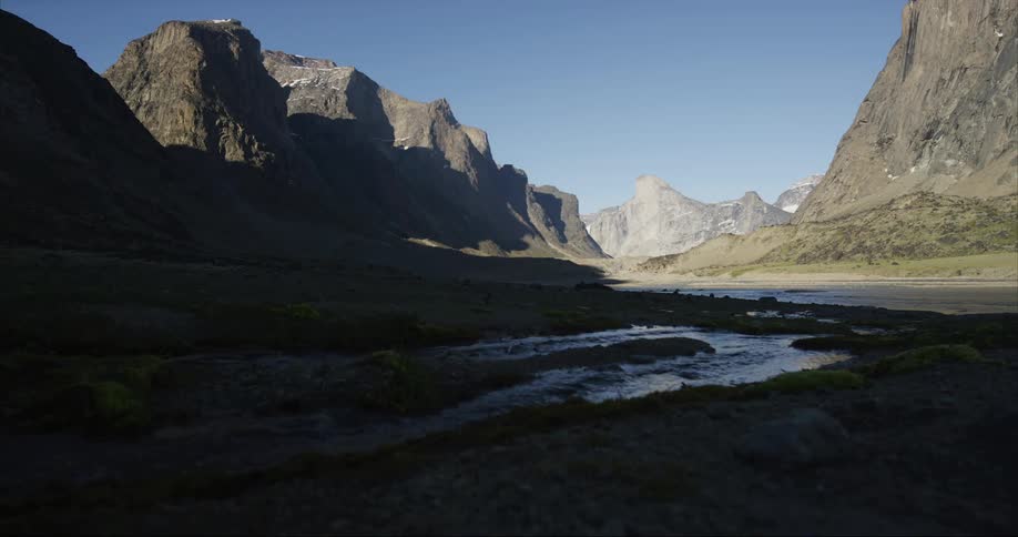 Mount Thor sits proudly as a small feeder creek bubbles in the foreground. Giant granite mountains frame this glacial river valley