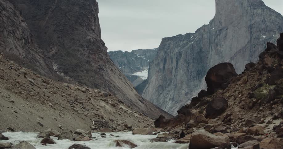 A stream cuts through a glacial moraine with Mount Thor towering above in the background