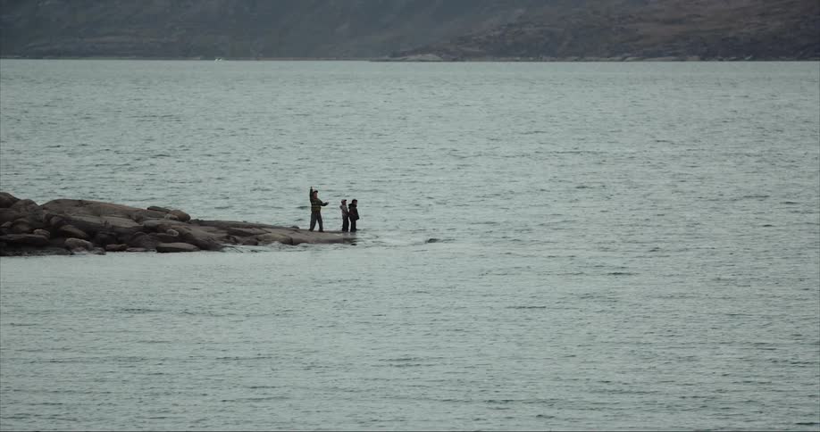 Kids playing and throwing rocks into the arctic ocean from the shoreline