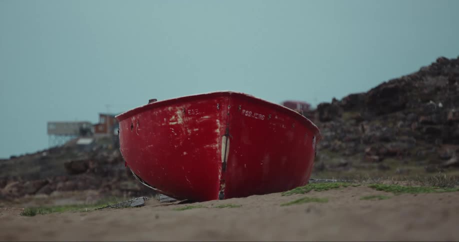 A beat up old boat sits on the land by the shore on Baffin Island