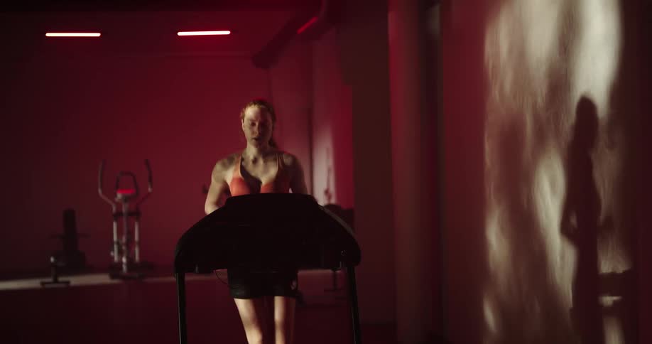 A woman jogs and then walks on the treadmill