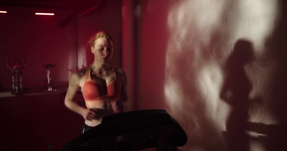 A woman jogs on a treadmill at the gym