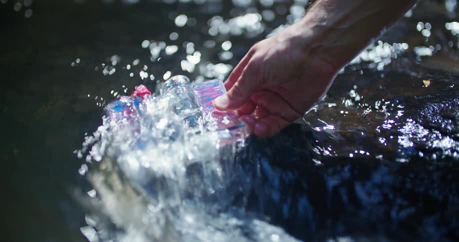 A man dips a water sample test kit in to a river and fills it with water