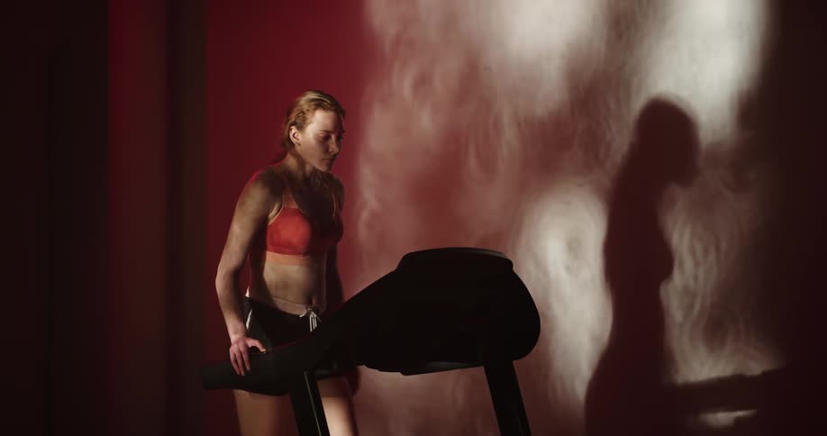 Woman casts shadow while walking on treadmill then speeding up to a jog