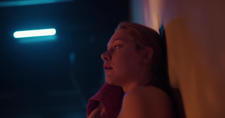 A teenage girl is leaning against a wall and wiping her face and neck with a dry washcloth