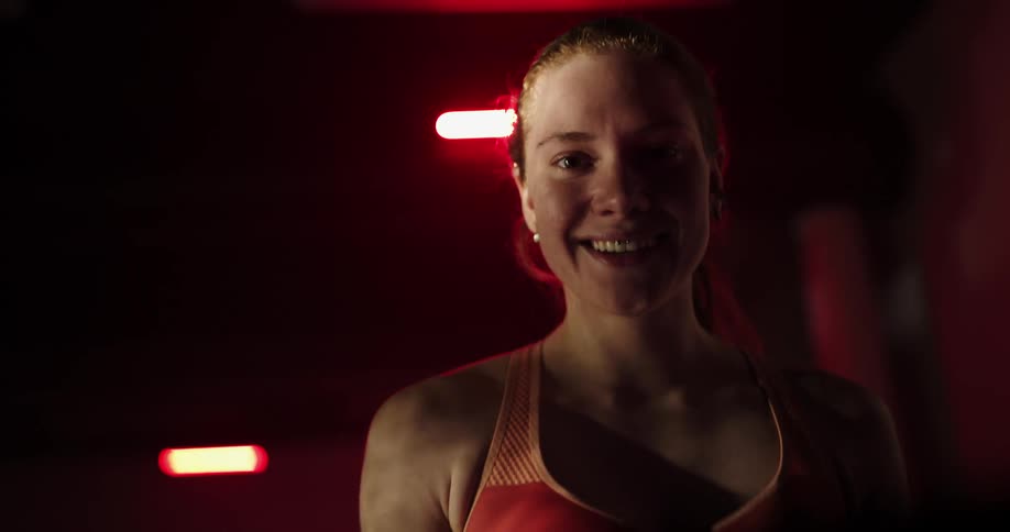 A woman smiles wide while walking on a treadmill