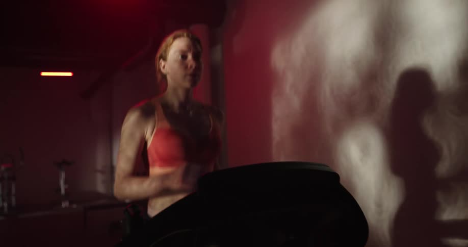 A woman jogs on a treadmill in a gym