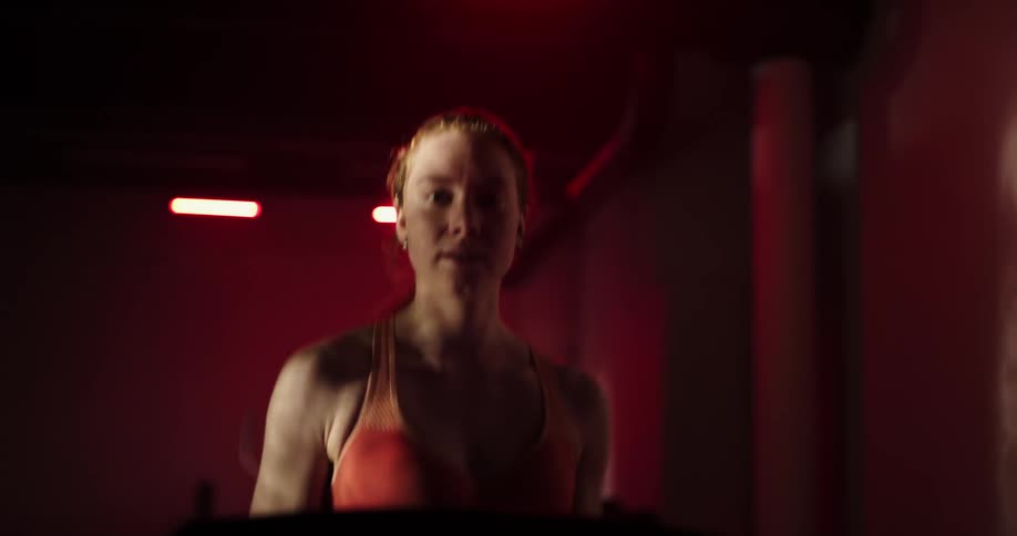 A woman in a pink sports bra running on a treadmill