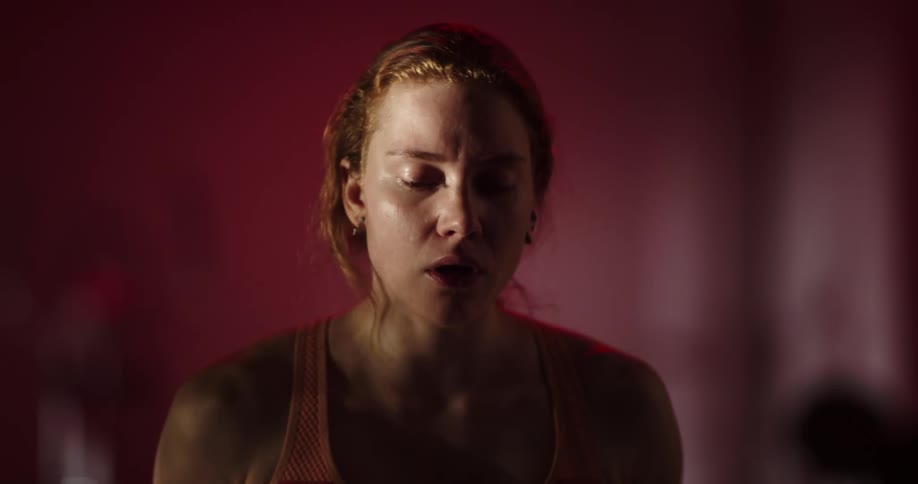 A woman drinking from a water bottle while walking on a treadmill