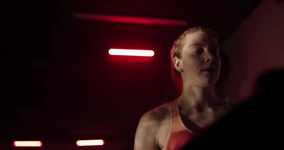 A woman is drenched in sweat as she jogs on a treadmill