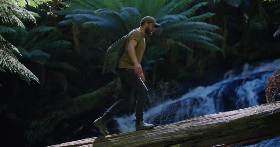 A man hikes over the log bridging the stream