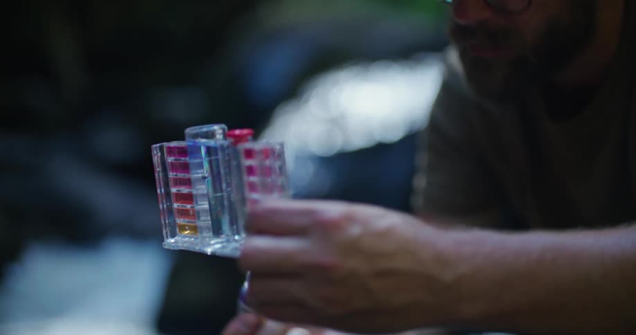 Man tests water using kit on riverbank