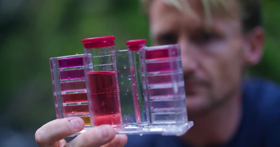 Man examines water sample testing kit
