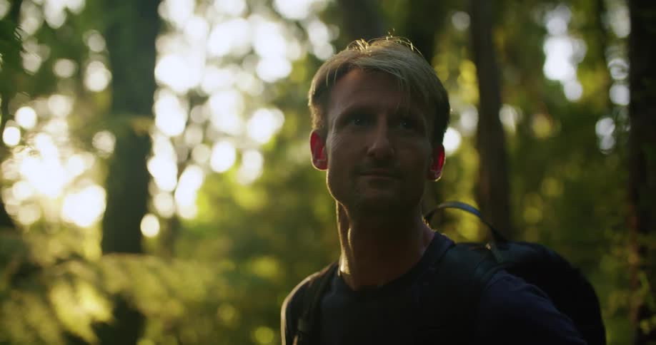 A man hiking in a forest with a backpack on a sunny day