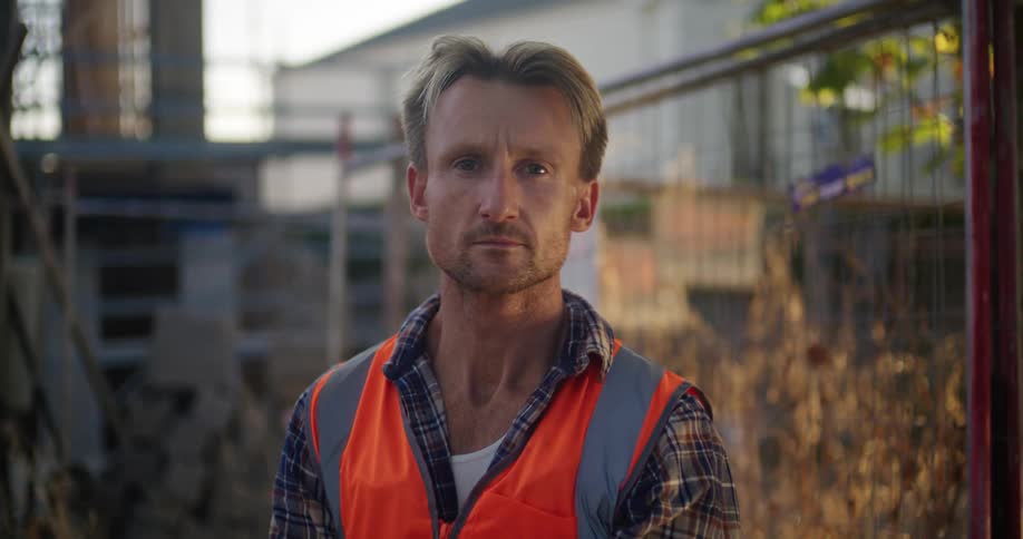 Worker poses near fence on worksite