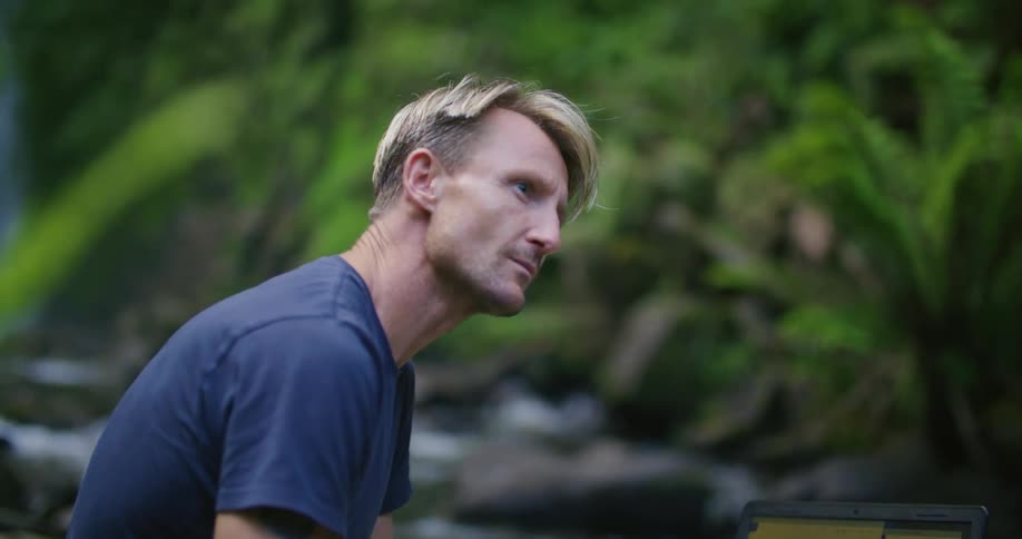 A male scientist logging data next to a river in nature