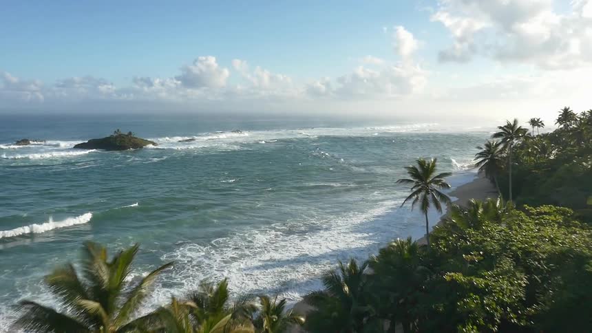 Travelling through a tropical landscape and towards rough seas on a semi-cloudy day