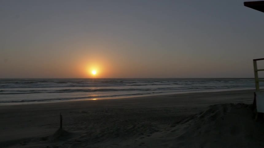 The sun sets on the horizon at an empty beach