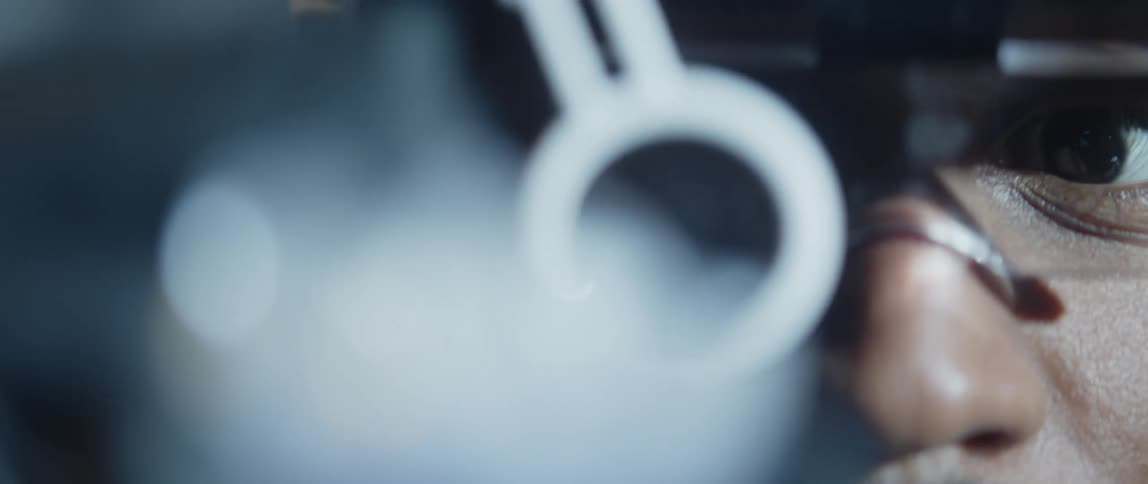 A man with microscope glasses looking closely at an object