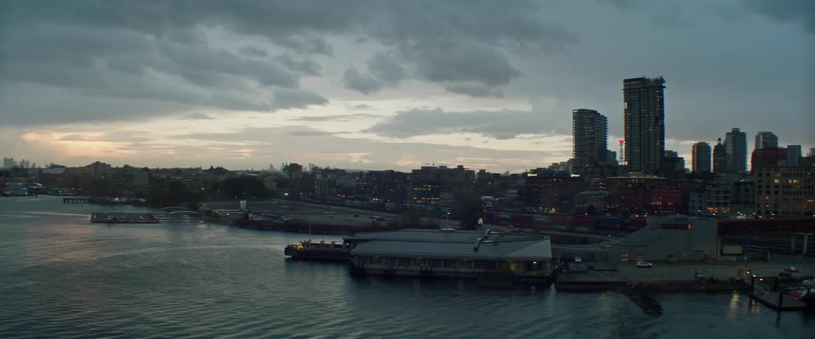 Skyscrapers and buildings on waterfront property in a city at dusk