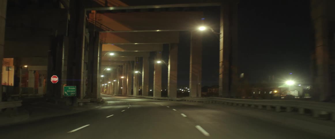 A highway tunnel is lit up at night under a bridge
