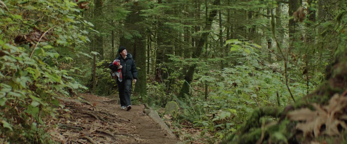 Woman with black hat coat and jeans hikes in the woods