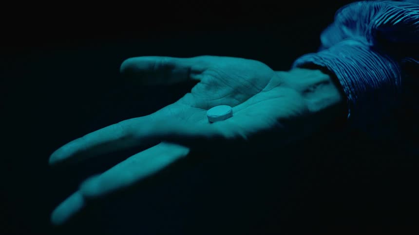 Person wearing shirt opens hand with pill in