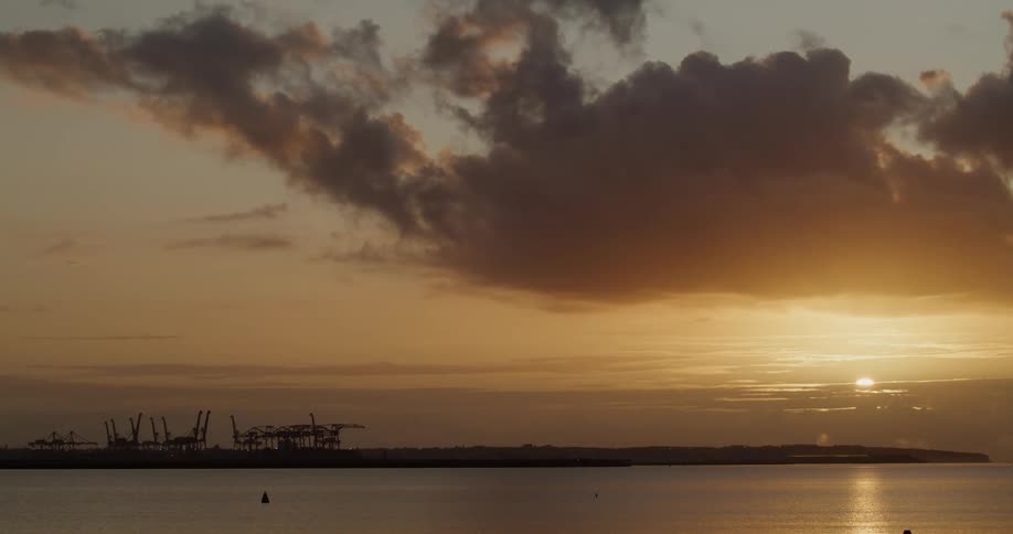 Sunlight shining through clouds reflecting off water with a strip of land in the distance