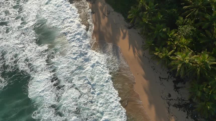 The tide flows in and waves crash along a beach shoreline