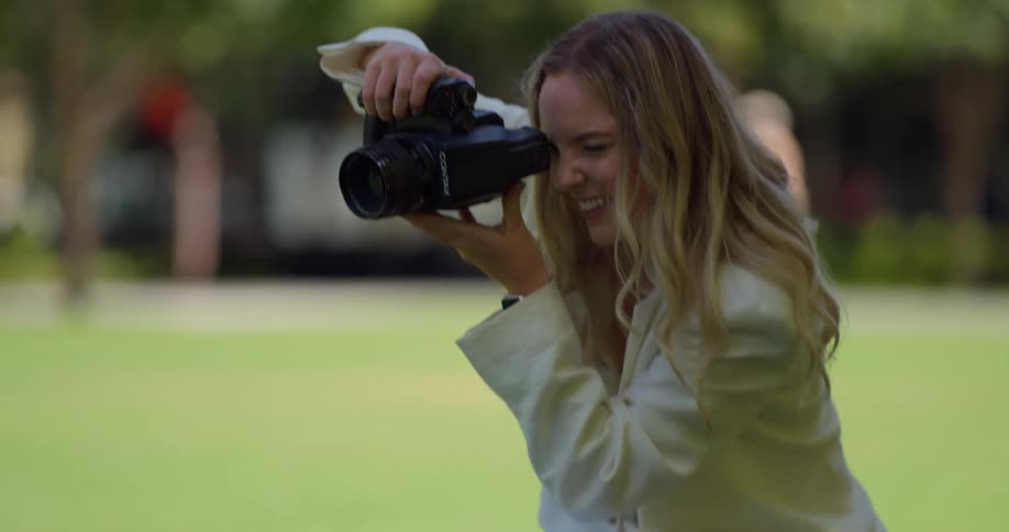 Woman smiles while filming with camcorder in park
