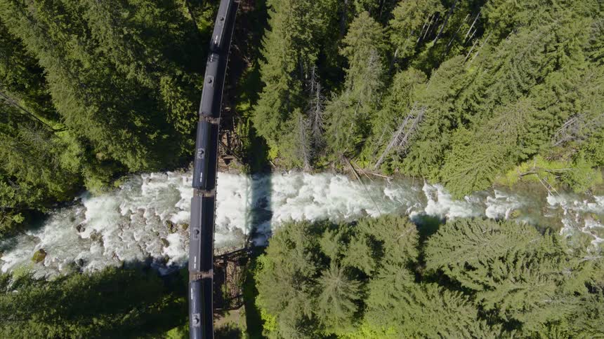 Overhead view of tank cars traveling high over a rushing river in a beautiful mountian forest