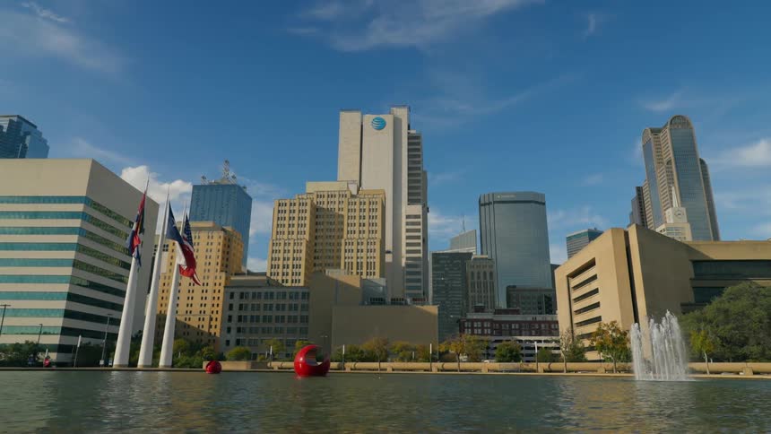 Large red open ball shapes and fountain sit in water just off waterfront near downtown