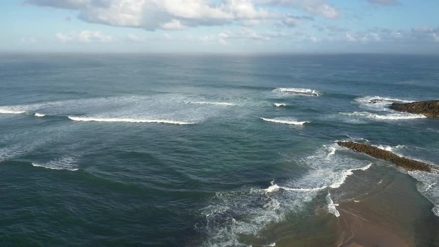 Waves roll onto a shore on a cloudy day