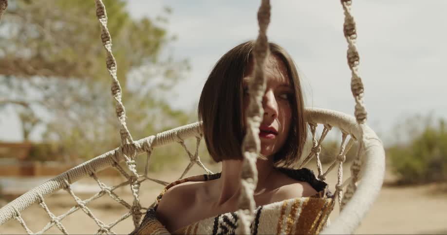 Woman sitting on a hanging chair in the desert.