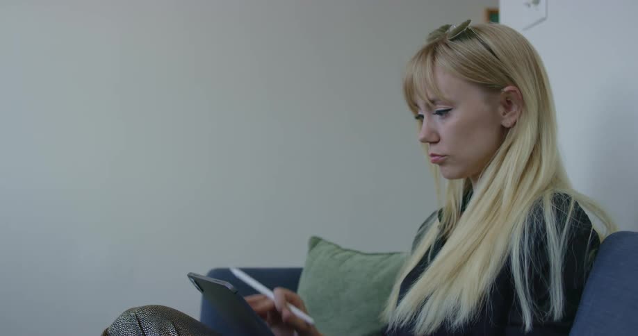 A woman in a room filled with instruments picks up a tablet and sits down to write on it