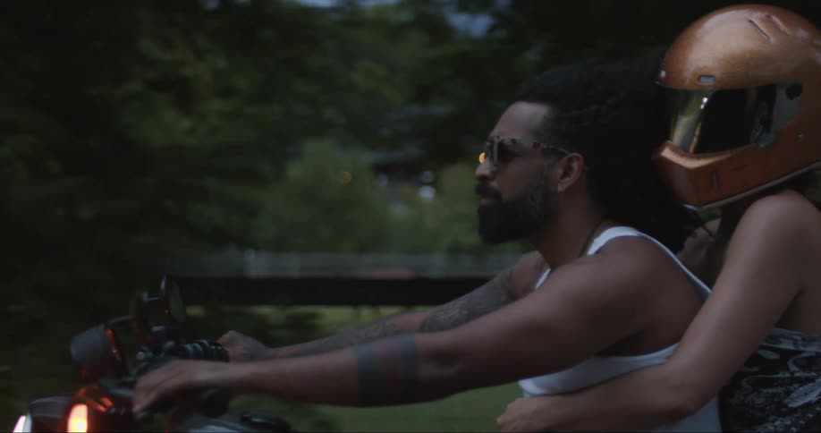 A woman sits on the back of a motorcycle with her arms around a man as he drives