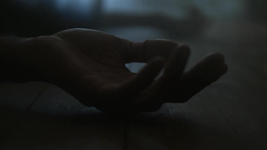 The fingers on the hand of a person lying on the floor bend and move