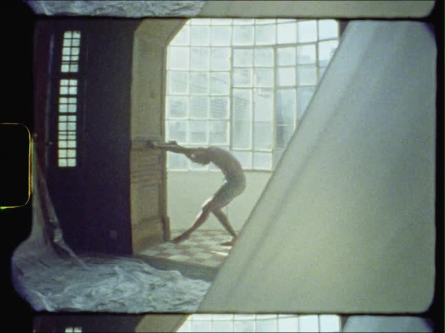 Male dancer dances in archway near windows showing other buildings