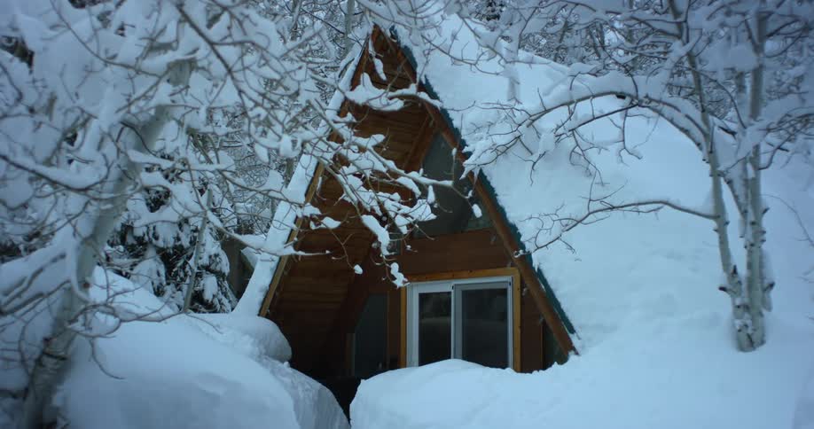 Heavy snow covers an a frame cabin in the woods