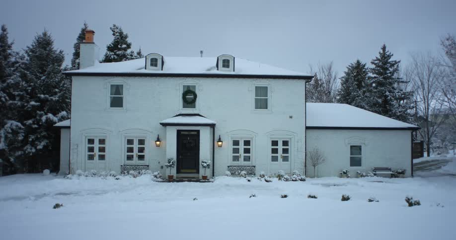 A white house surrounded by snow on a winter evening