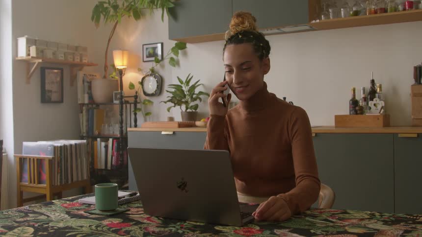 A woman using a laptop while talking on the phone