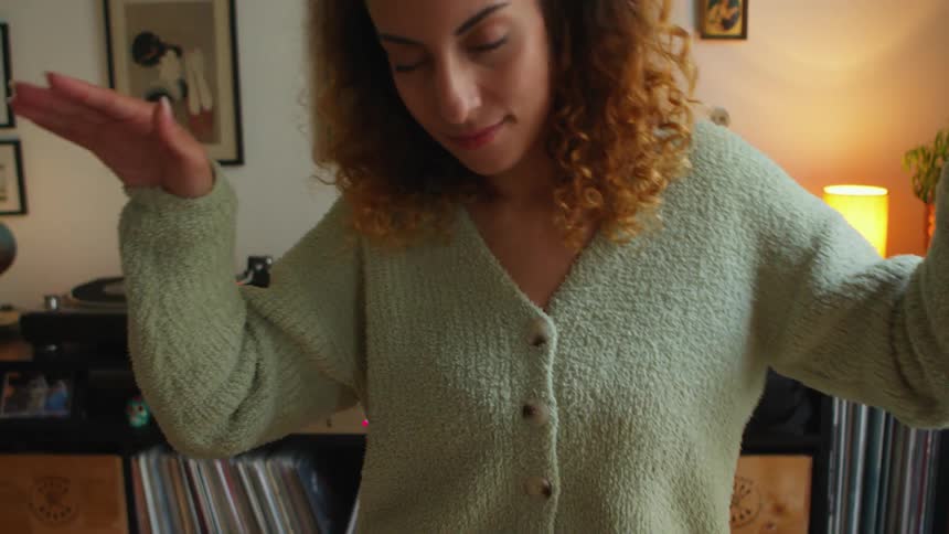 A woman dances while listening to an album at home