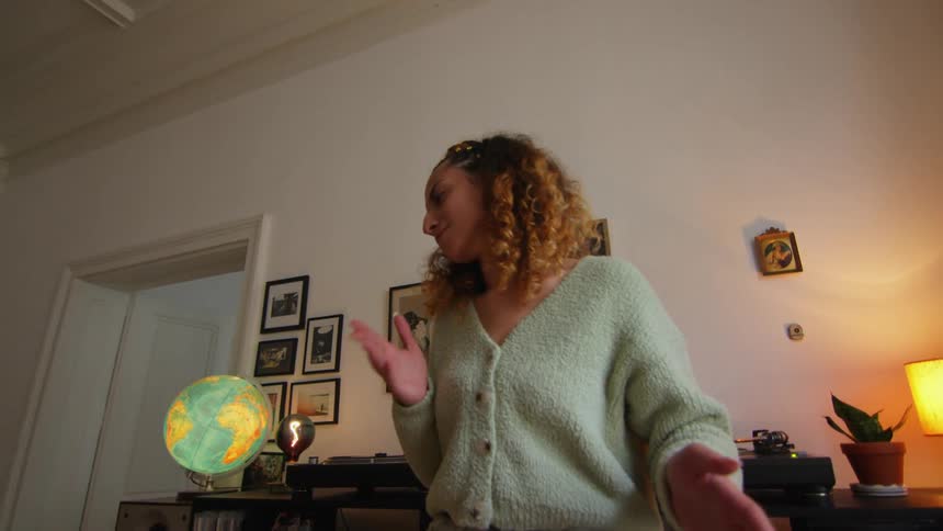 A woman dances while listening to music in her living room