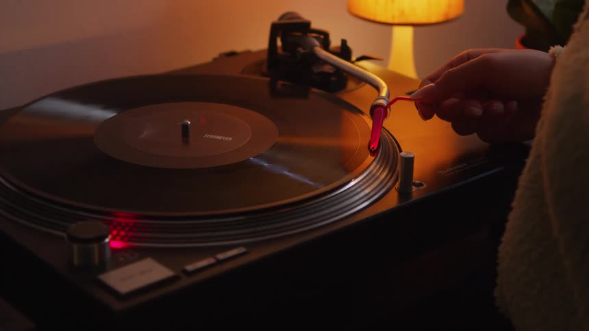 A woman moves the needle arm on her record player