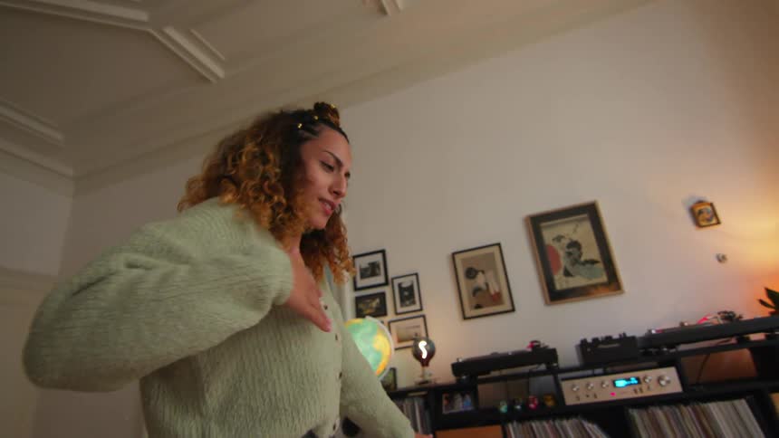 A woman dances to music in her living room