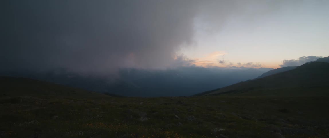 Mist rolling over the valley of a dark mountainside before the sun comes up