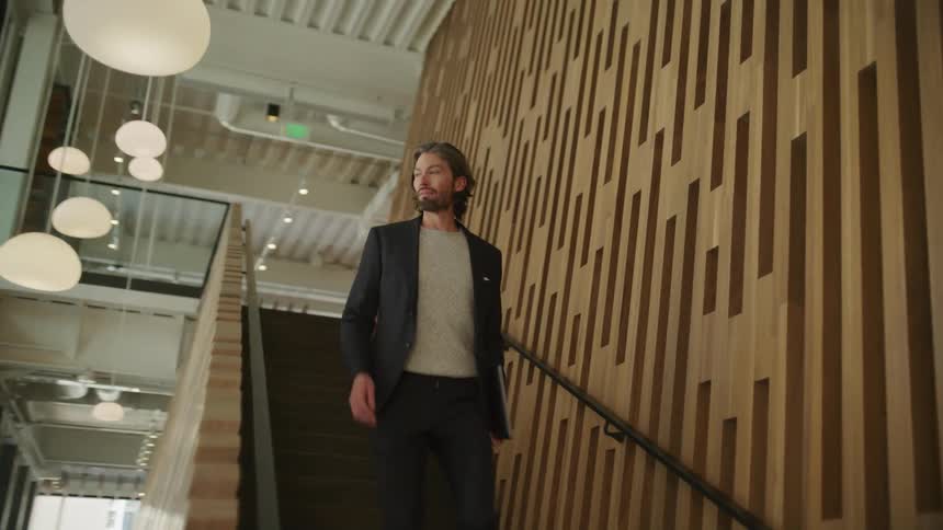Businessman with beard and blazer jacket goes downstairs in the office building