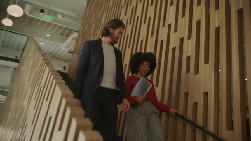 Businessman and business woman go downstairs in the office building